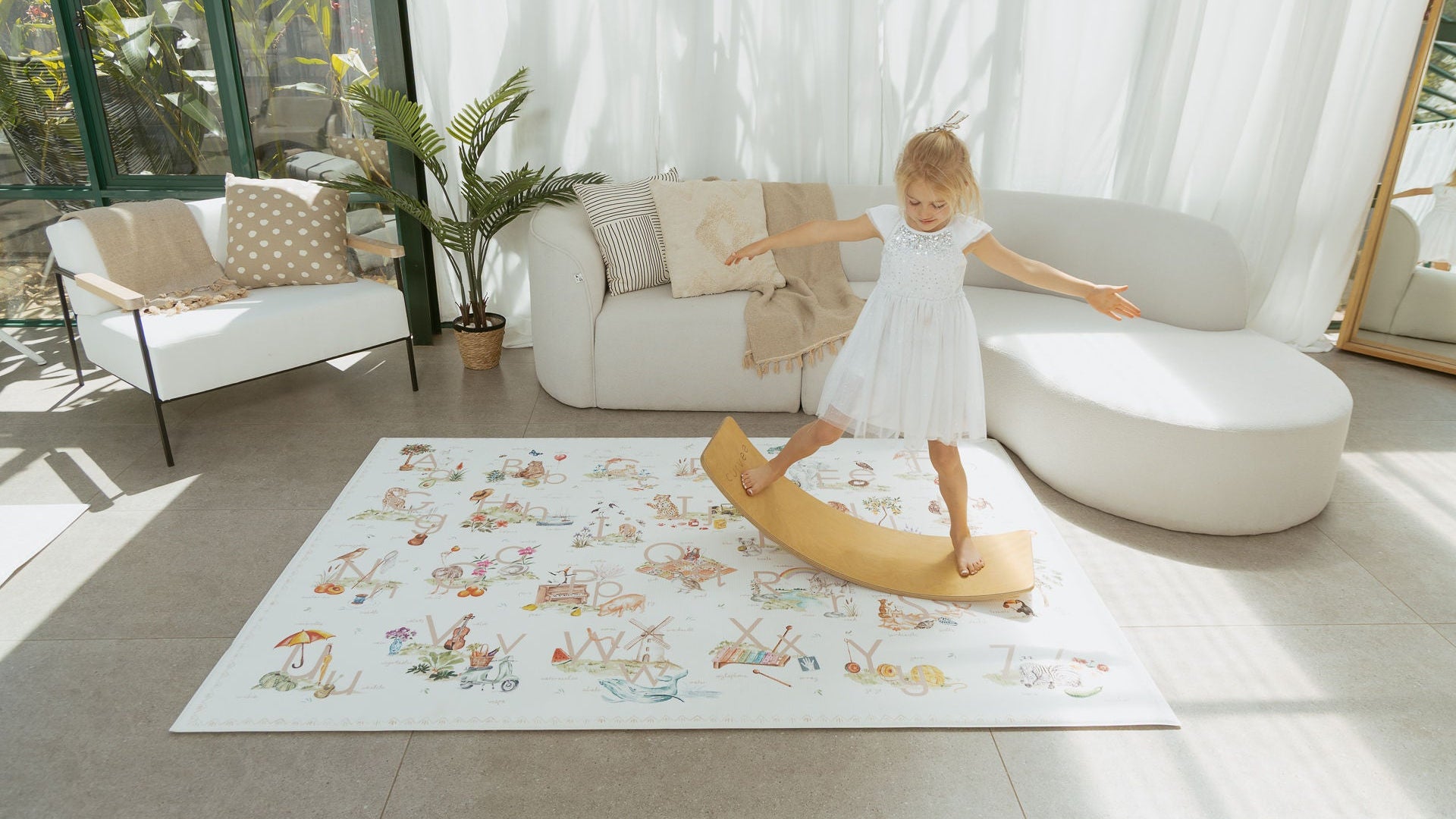 Child playing on a rug with a colorful design in a bright living room.